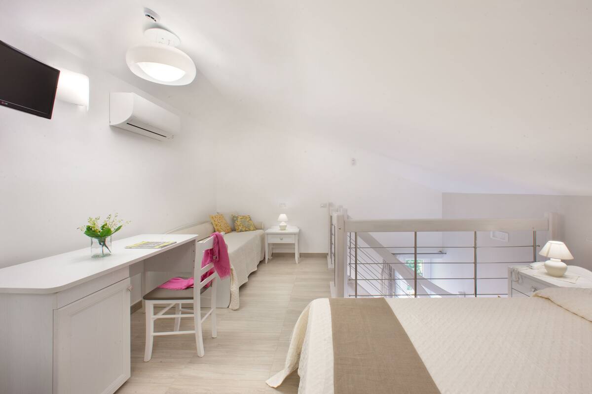 A modern bedroom with a desk, a bed, and a balcony.