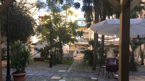 A covered outdoor area with a tiled walkway, potted plants, and a seating area. - B&B Liberty 900 (Catania)