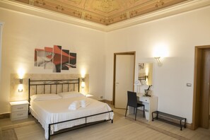 A hotel room with a bed, bedside tables, a desk, a chair, a mirror, and a door. - B&B Liberty 900 (Catania)