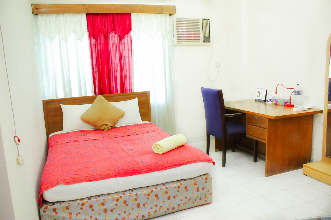 A hotel room with a bed, a desk, and a chair.