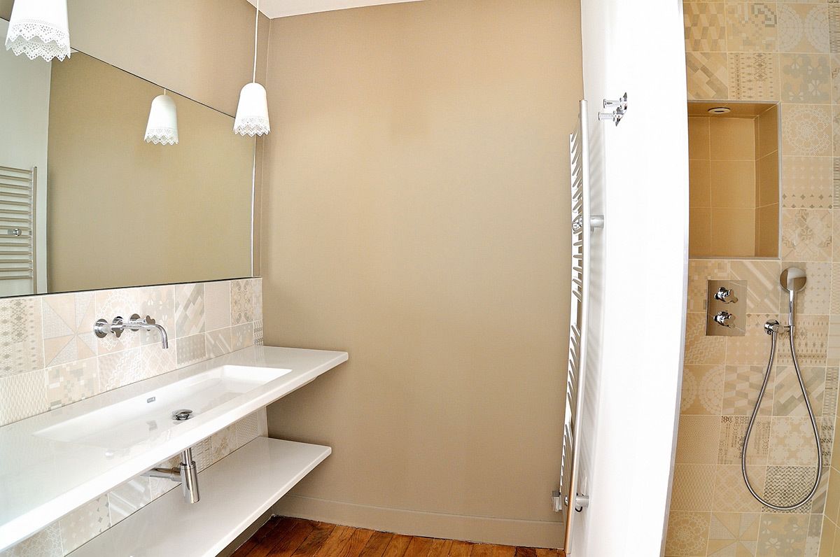 A bathroom with a white sink, a mirror, and a shower area.