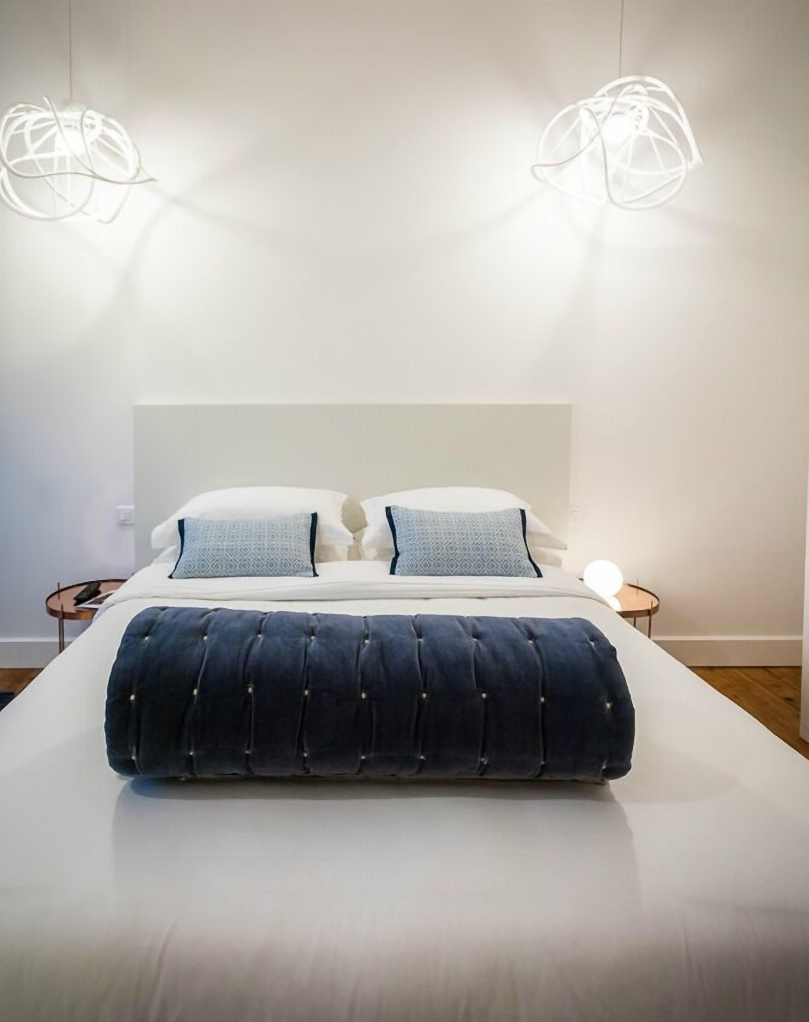 Een moderne slaapkamer met een groot bed, twee nachtkastjes en twee hanglampen.
