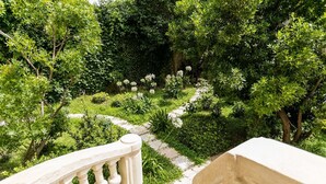 A stone balustrade overlooking a lush garden with a variety of plants and a stone pathway. - L'Hôtel Particulier Béziers (Béziers)