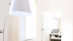 A bedroom with a bed, pillows, a hanging lamp, a window, and a bathroom visible through an open door. - L'Hôtel Particulier Béziers (Béziers)