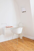 Un baño moderno con una bañera blanca, un tocador blanco con una bandeja dorada rosa y un accesorio de luz blanco instalado en la pared.