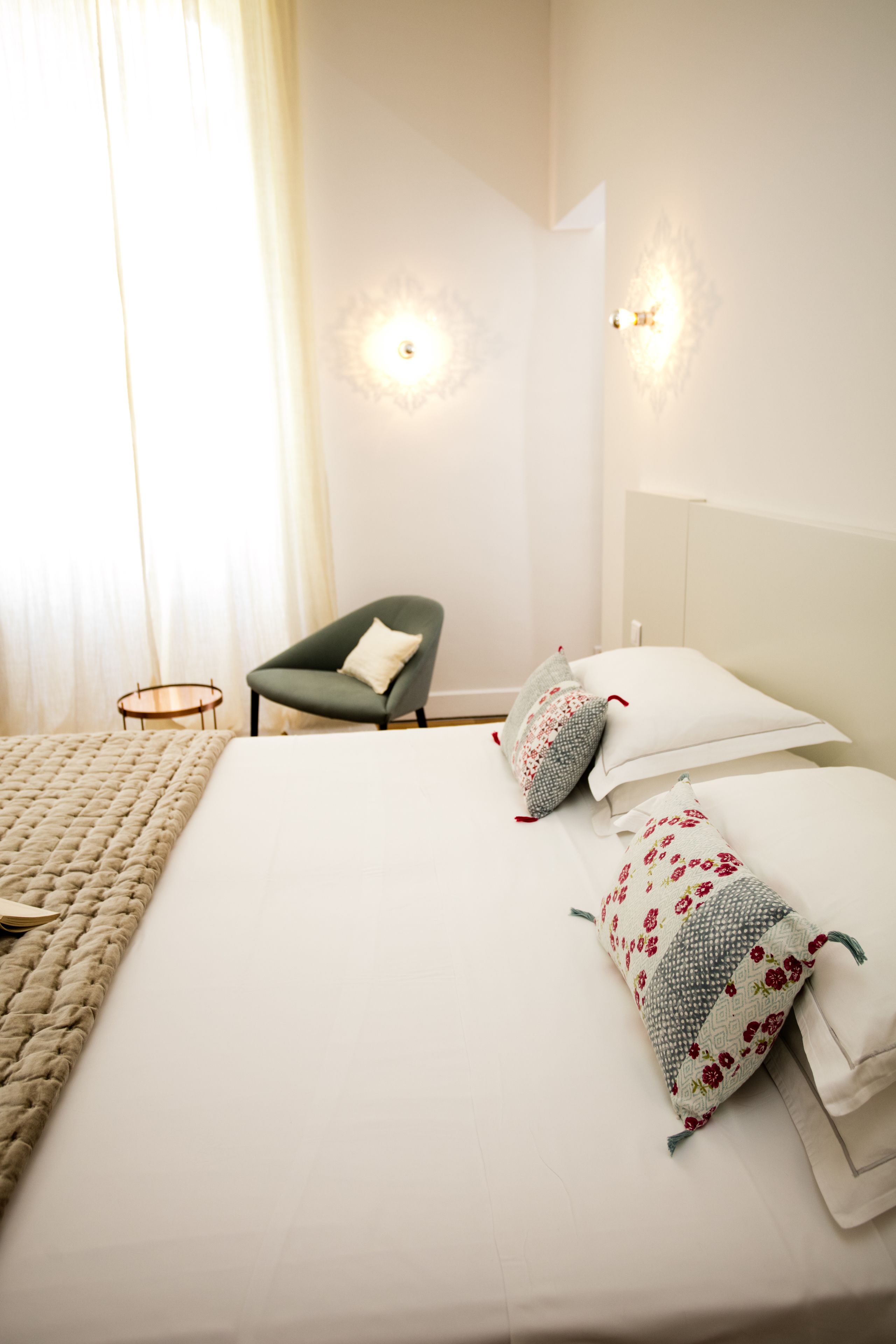 Ein ordentlich eingerichtetes Hotelzimmer mit einem großen Bett, einem Sessel und einem kleinen Tisch.