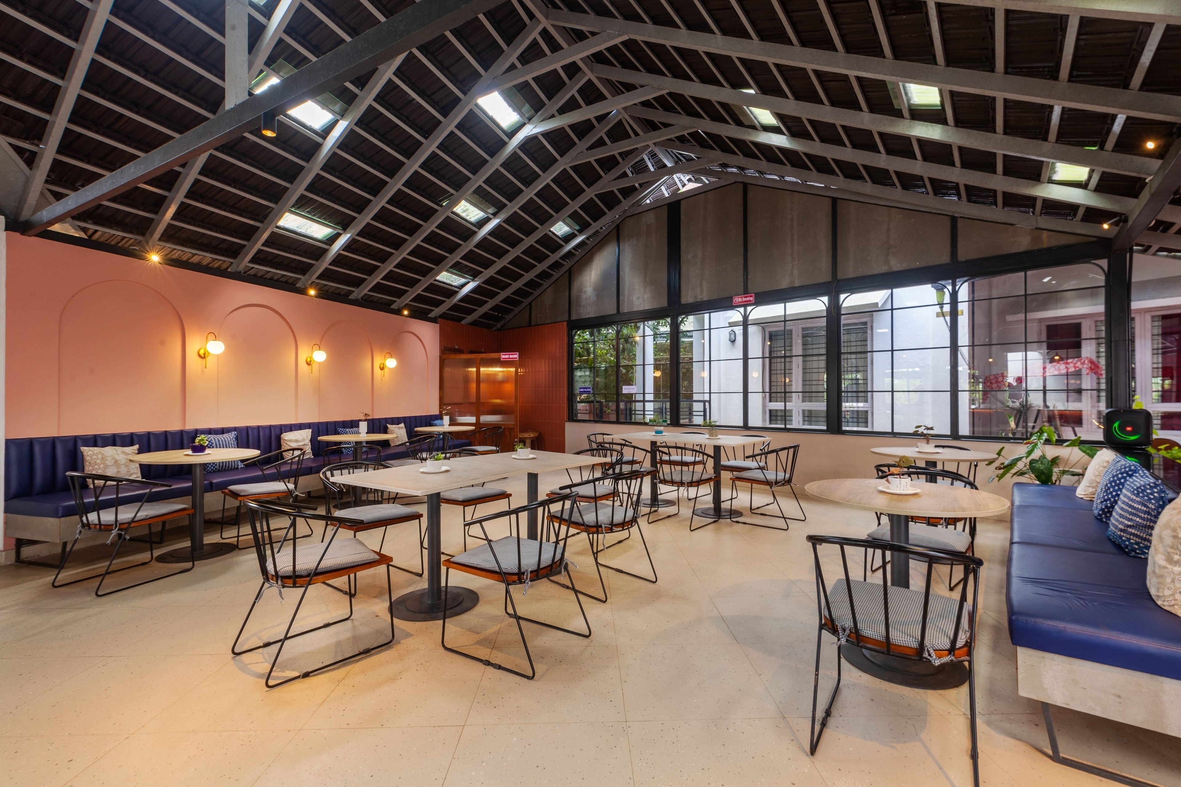 A spacious indoor dining area with high ceilings, large windows, and a mix of seating options including tables and benches.