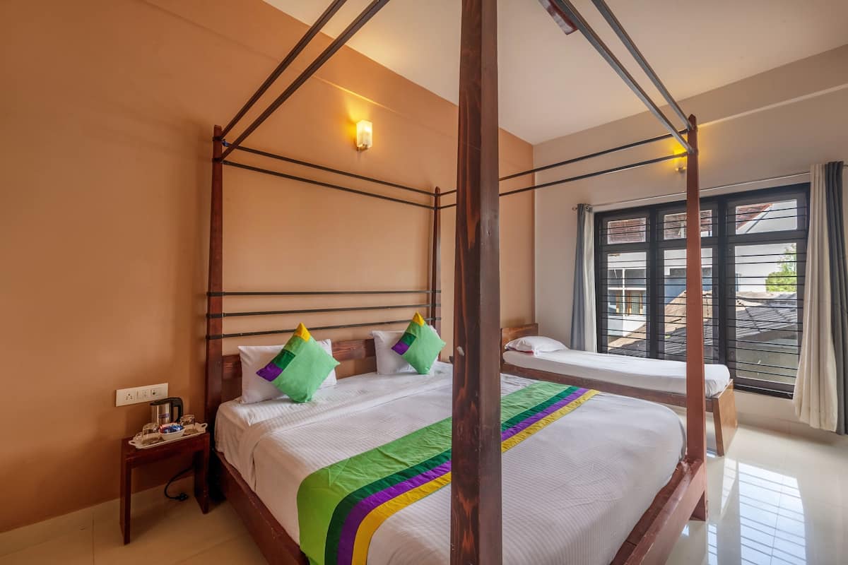 Una cama con dosel, una mesita de noche con lámpara y una ventana con cortinas.