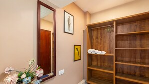 A hallway with a wooden wardrobe, a mirror, and a vase of flowers. - Treebo Vrindavan, 3 Km From Madikeri Fort (Madikeri)