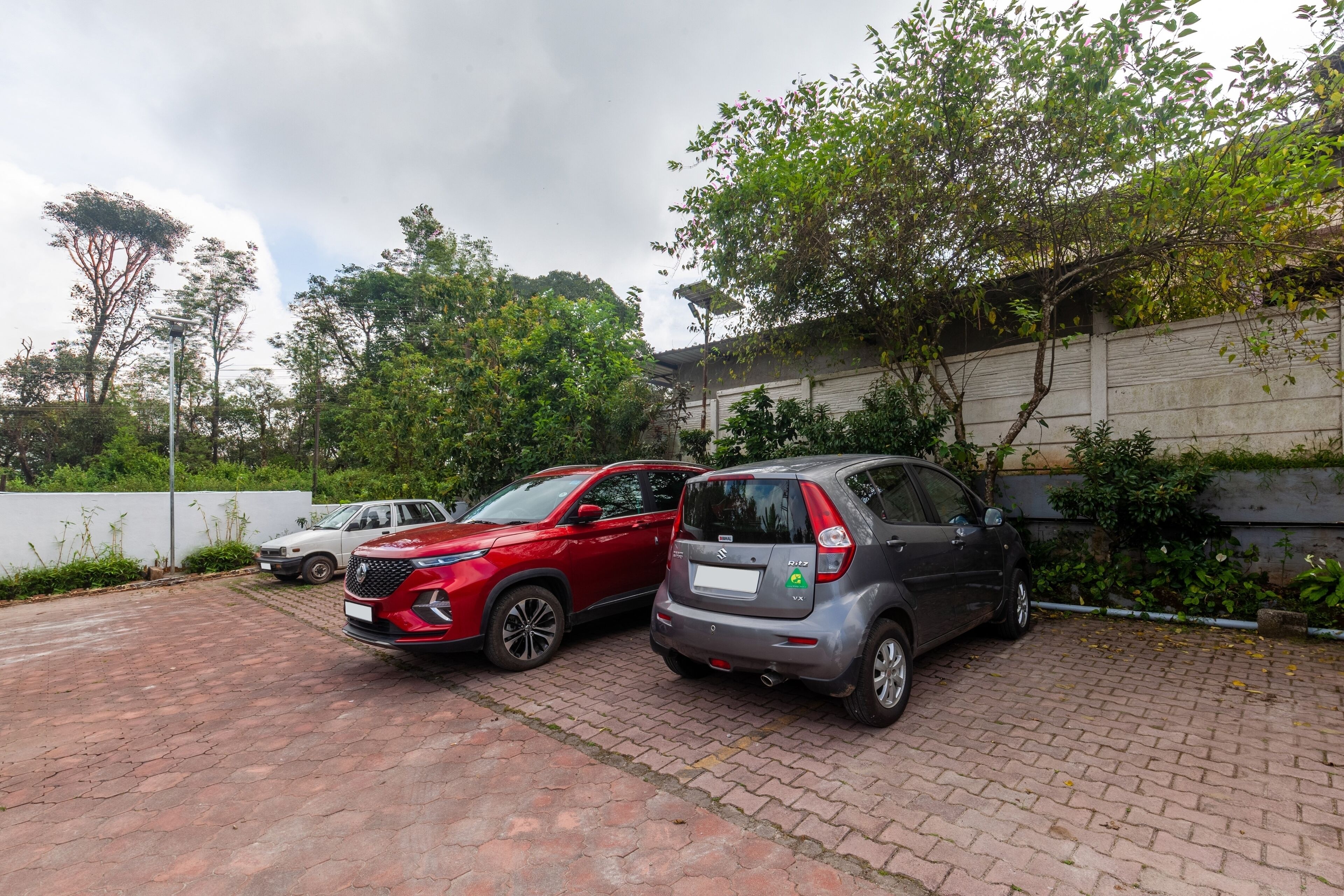 A parking area with two cars parked on a brick surface.