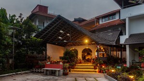 A building with a covered entrance, outdoor seating, and potted plants. - Treebo Vrindavan, 3 Km From Madikeri Fort (Madikeri)