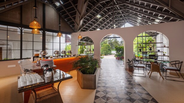 A spacious indoor area with a high ceiling, large windows, and a reception desk. - Treebo Vrindavan, 3 Km From Madikeri Fort (Madikeri)