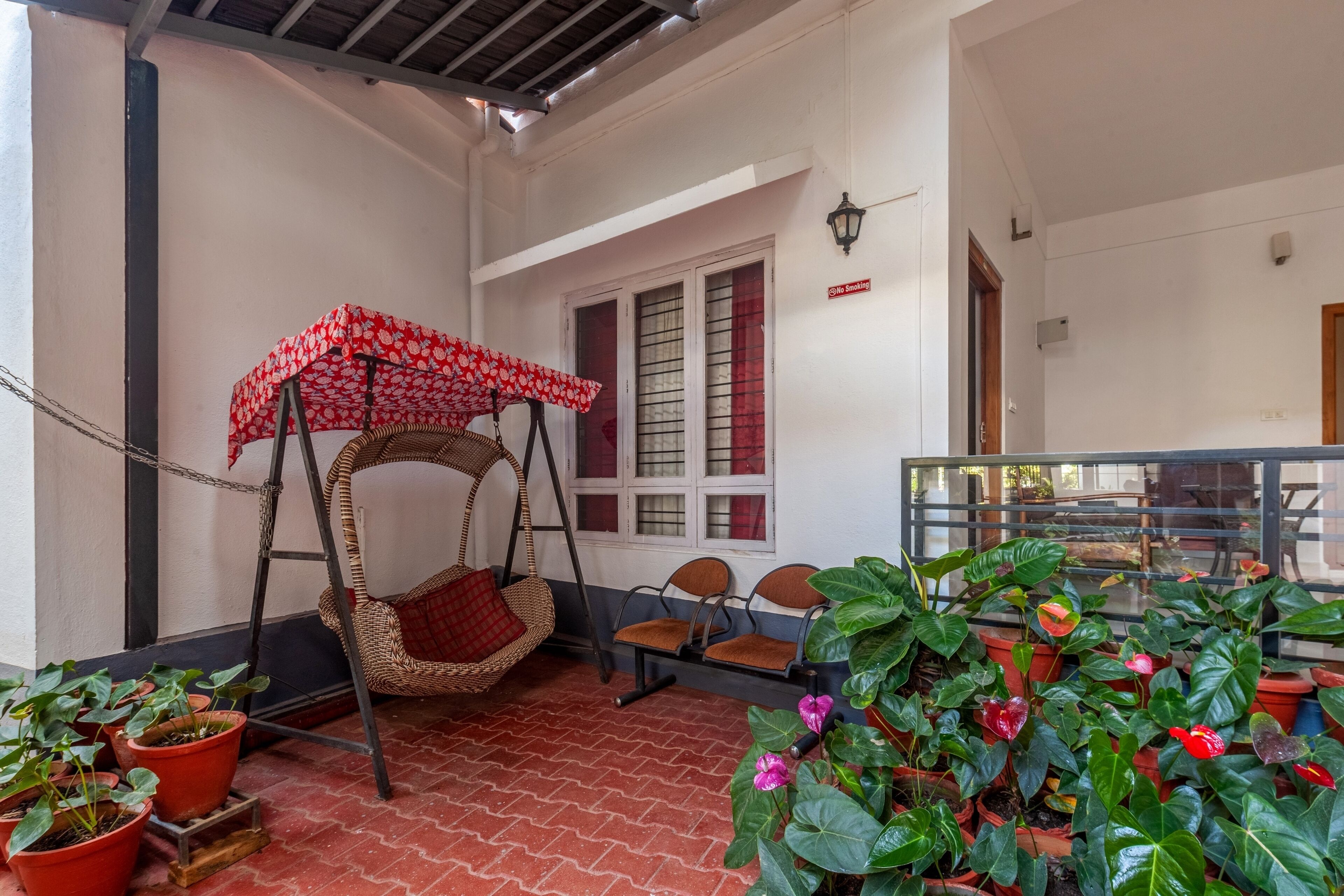 A covered seating area with a swing chair, potted plants, and a 'No Smoking' sign.