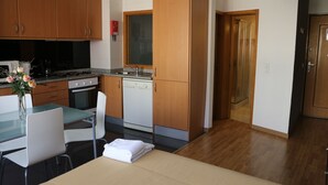 A compact kitchen with wooden cabinets, a dining table with chairs, and a small countertop. - Studios Porto Solar (Porto)