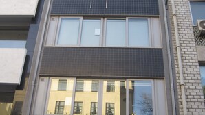 A multi-story building with a mix of window styles and a visible red awning at the ground level. - Studios Porto Solar (Porto)
