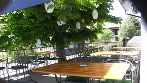 An outdoor café with tables and chairs under a tree.