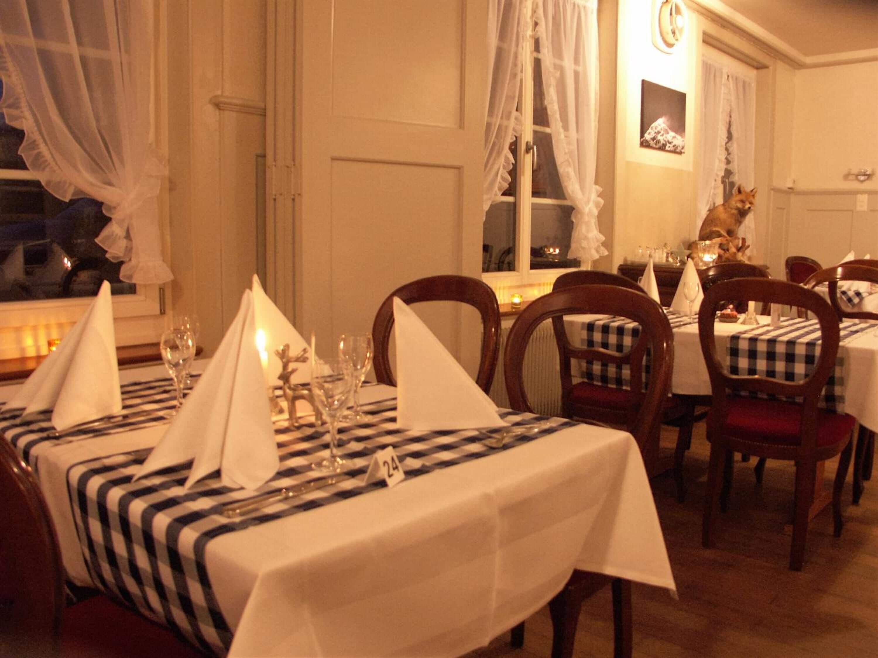 Un comedor con manteles a cuadros, sillas de madera y una vela sobre la mesa.