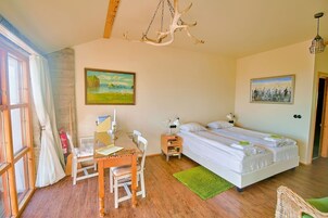 A bedroom with a bed, a desk, and a chair. There is a painting on the wall and a chandelier.