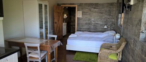 A compact bedroom with a bed, a small table, a chair, and a green rug.