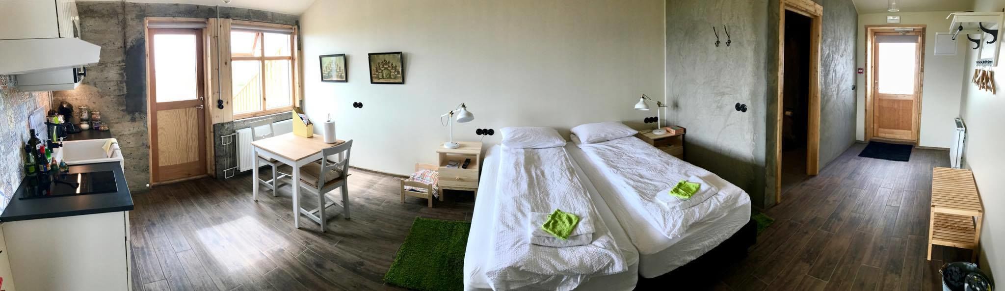 A room with two beds, a desk, a chair, a small table, and a radiator.