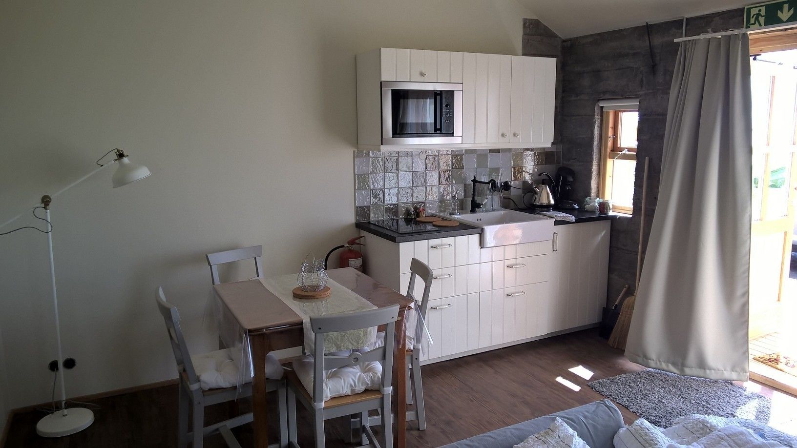 A compact kitchen with white cabinets, a microwave, and a small dining area with a table and chairs.