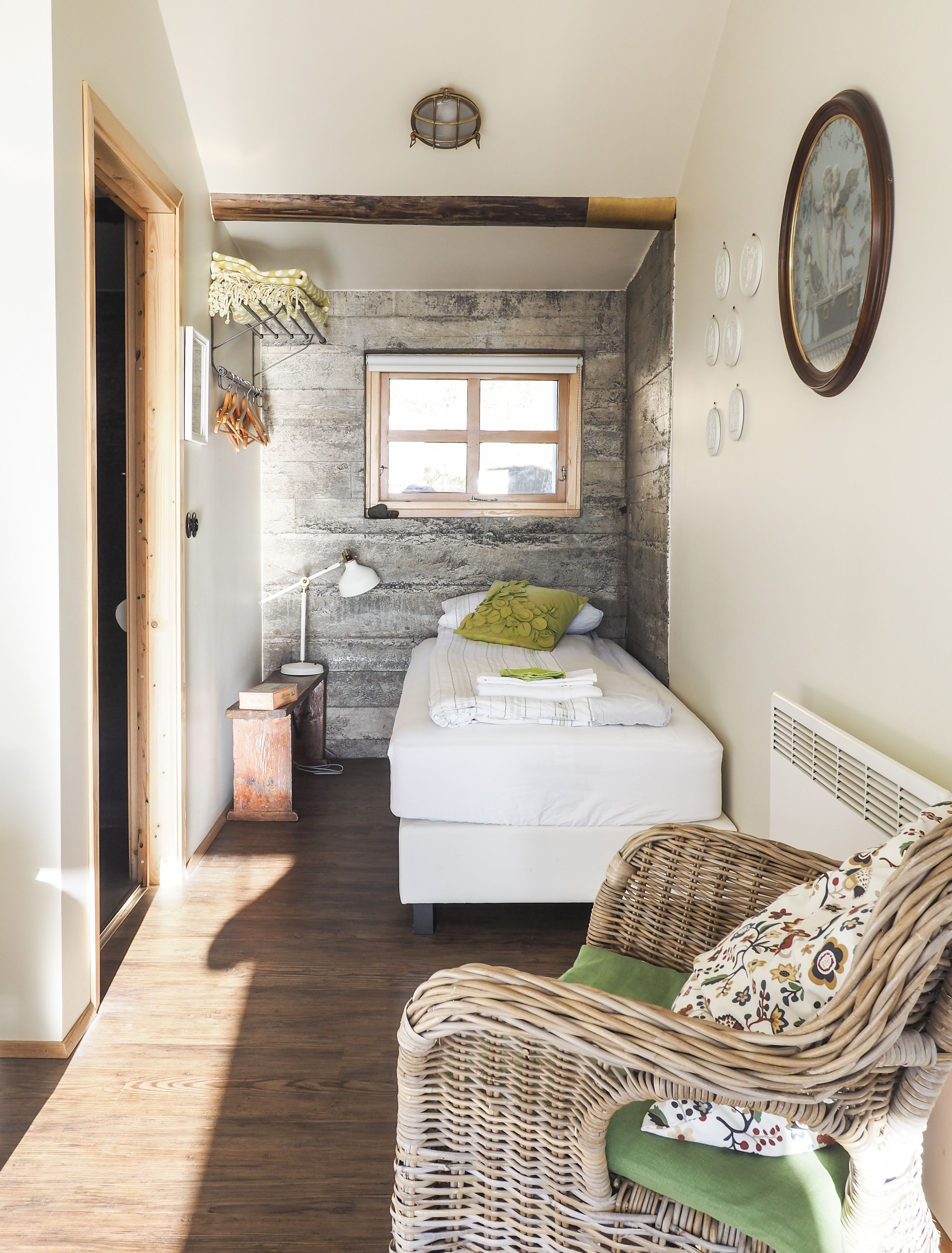 A cozy bedroom with a large bed, a wicker chair, a small table, and a window with a view.