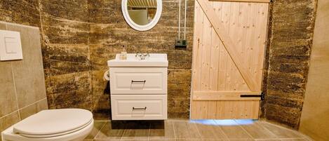 A bathroom with a toilet, a sink with a mirror, and a wooden door.