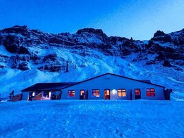 Una montaña nevada con un edificio que tiene varias ventanas y una puerta.
