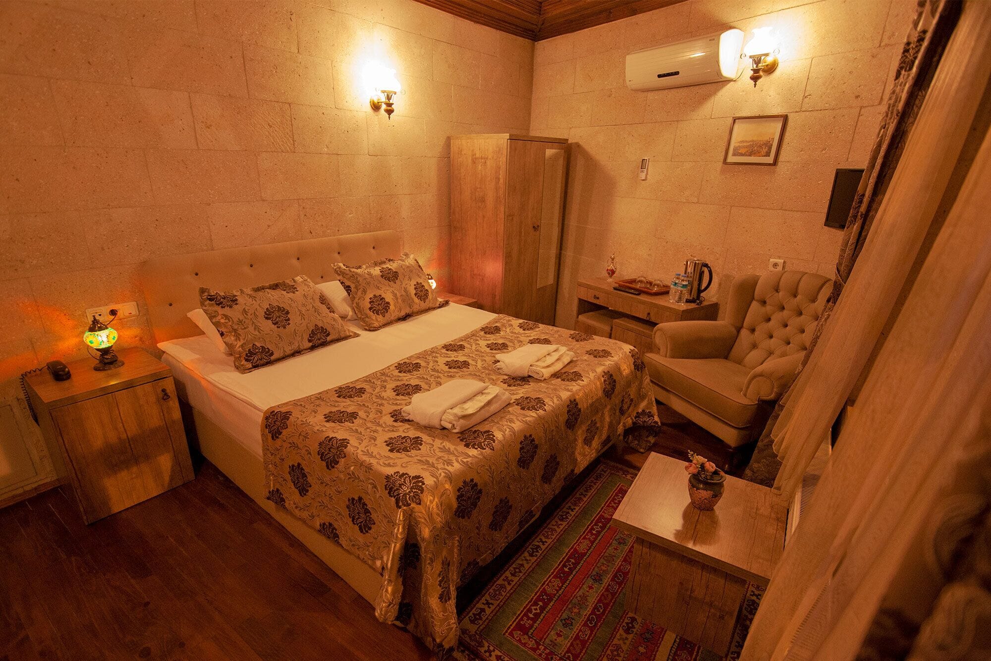 A cozy bedroom with a bed, bedside table, lamp, and a chair.