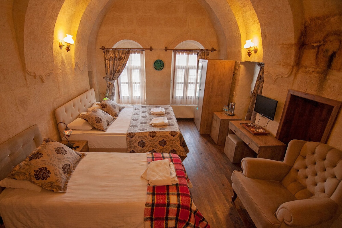 A cozy room with a bed, a sofa, a chair, and a television.