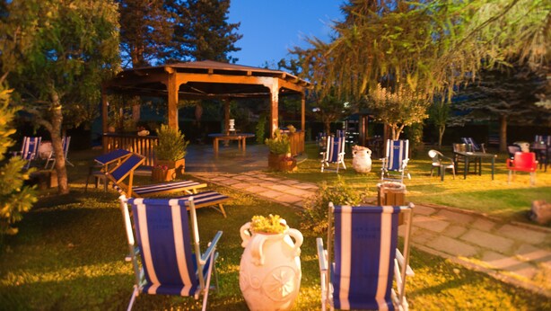 A gazebo with a stone pathway leading to it, surrounded by lounge chairs and potted plants. - Magnola Palace Hotel (Ovindoli)