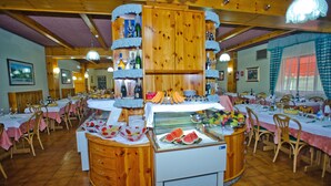 A restaurant with wooden decor, multiple dining tables, and a central display case with food items. - Magnola Palace Hotel (Ovindoli)