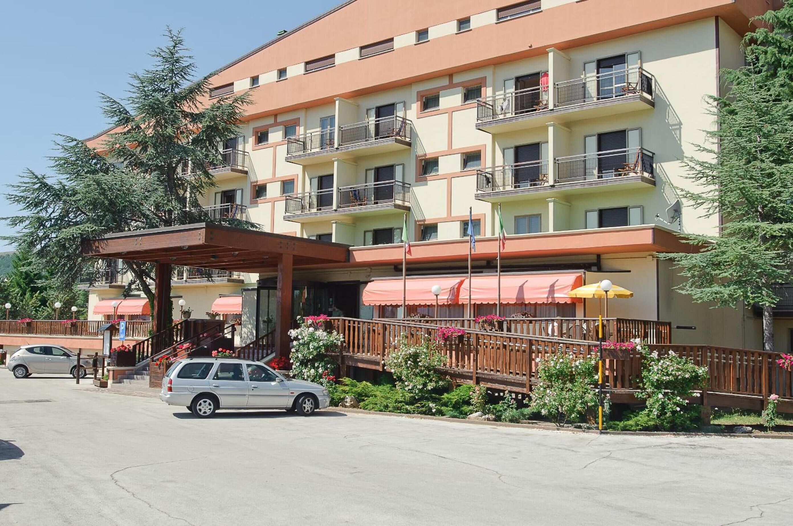 Un hotel a più piani con balconi, un ingresso coperto e un'area parcheggio.