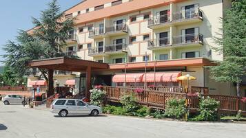 Un hotel a più piani con balconi, un ingresso coperto e un'area parcheggio.