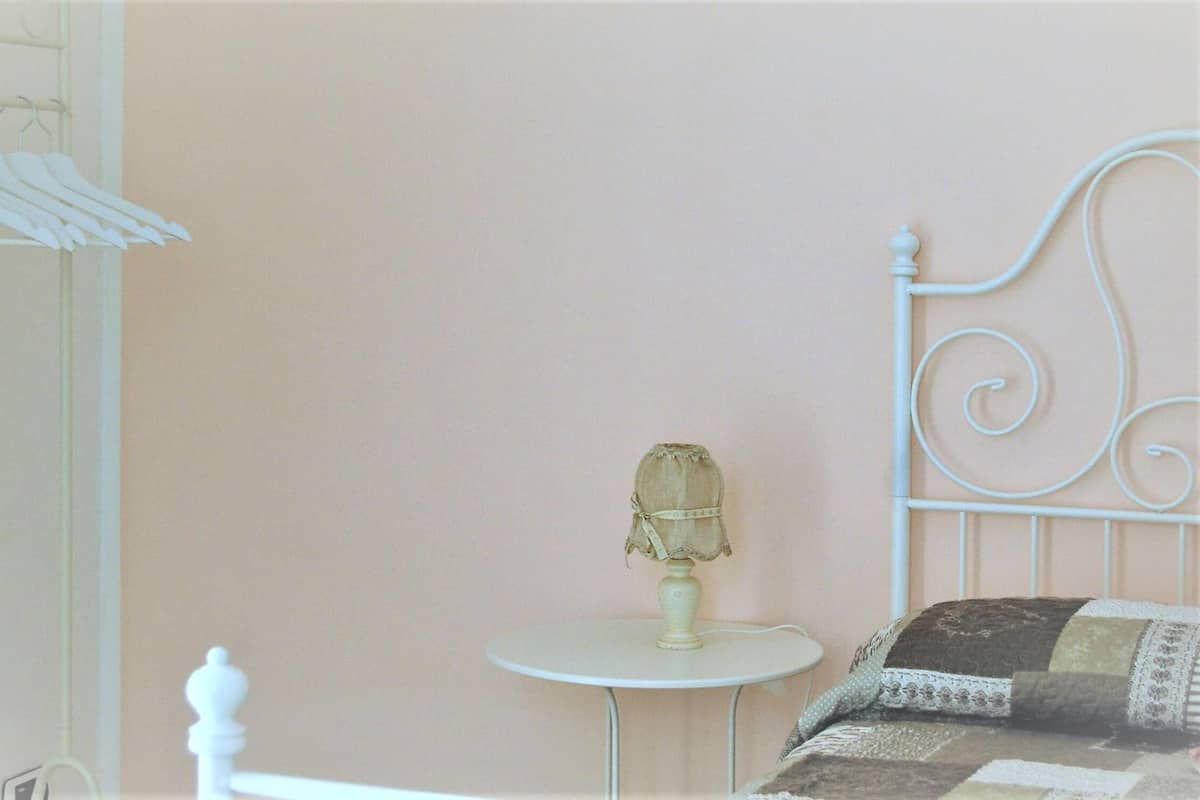 A bedroom with a bed, a small round table, and a lamp.