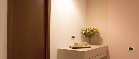 A bathroom with a wooden door, a white sink with a tray, and a vase of flowers.