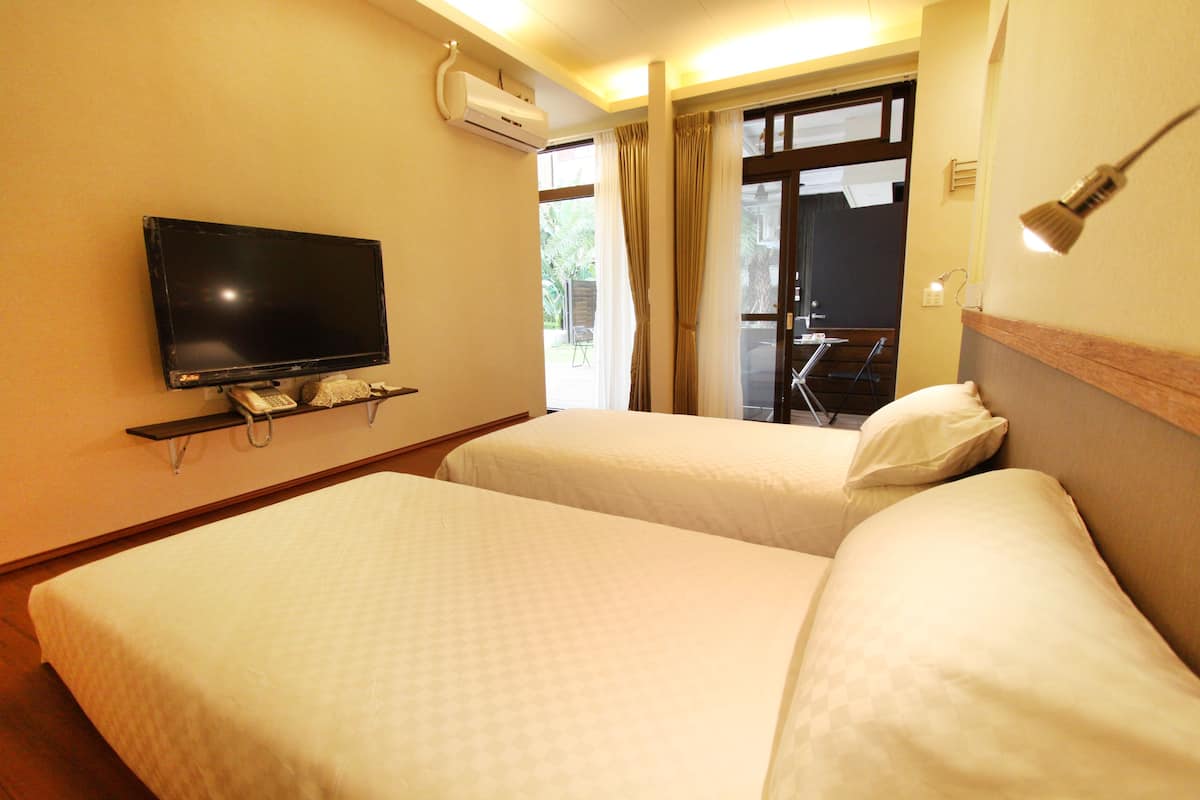 A hotel room with two beds, a TV, and a window with curtains.