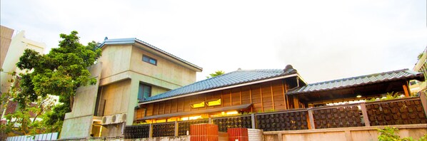 A traditional Japanese building with a tiled roof, wooden structure, and a balcony with a lattice fence.