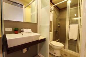 A bathroom with a white sink, mirror, and toilet.