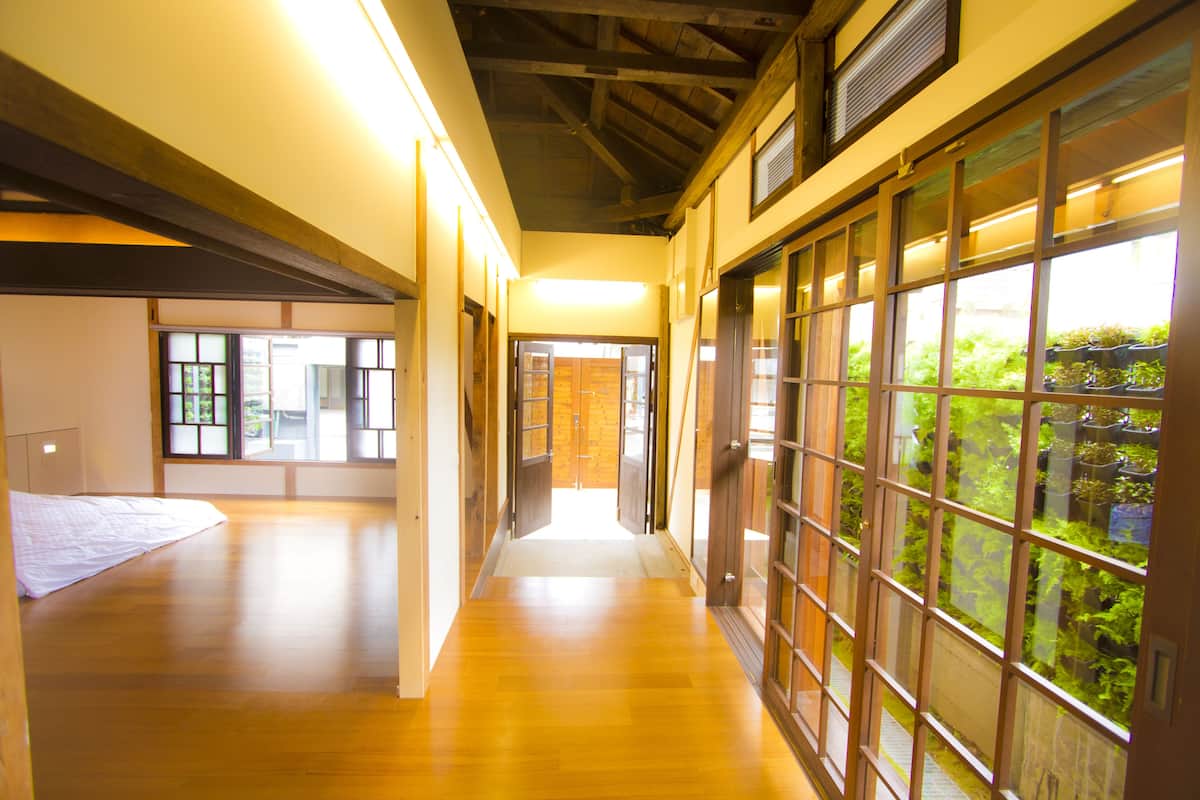 A corridor with wooden flooring, large sliding doors with glass panels, and a view of greenery outside.