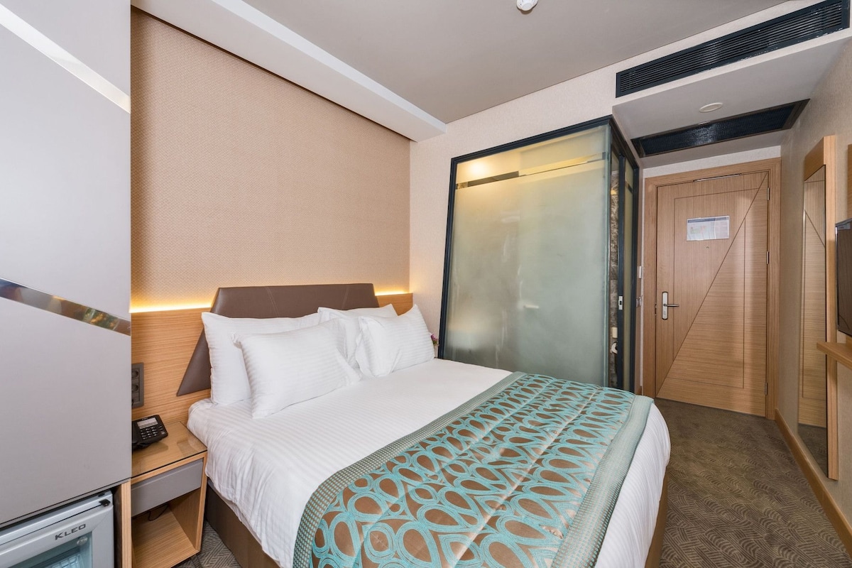Une chambre d’hôtel comprenant un lit, une table de chevet, une lampe et une armoire.