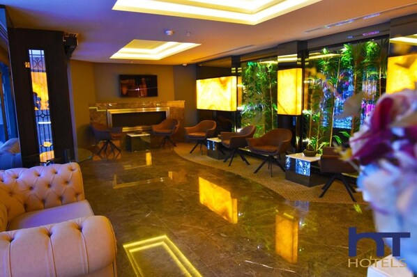 A hotel lobby with a plush seating area, a reception desk, and a wall with a vertical garden.