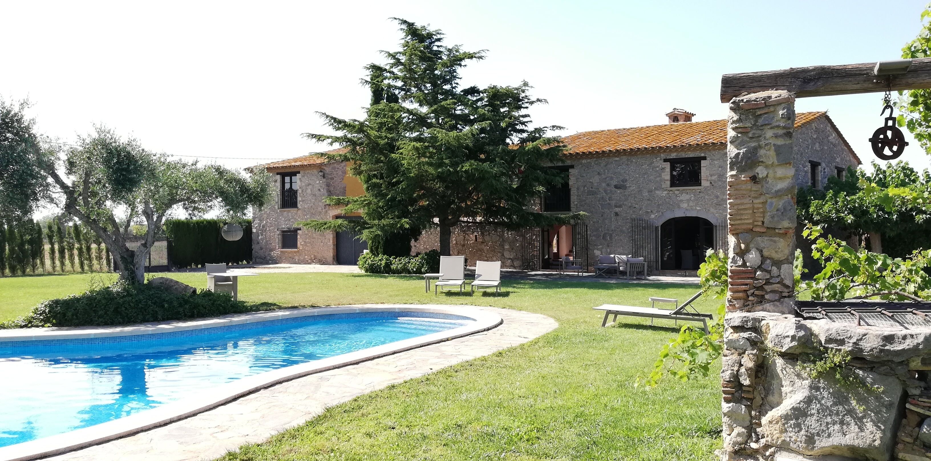 Ein Steinhaus mit Swimmingpool, Außenbereich zum Sitzen und einem Weinberg.