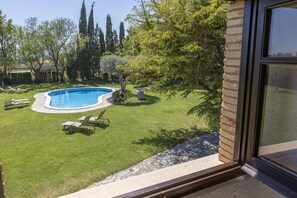 Ein Garten mit Schwimmbecken, umgeben von einem gepflegten Rasen und Bäumen.