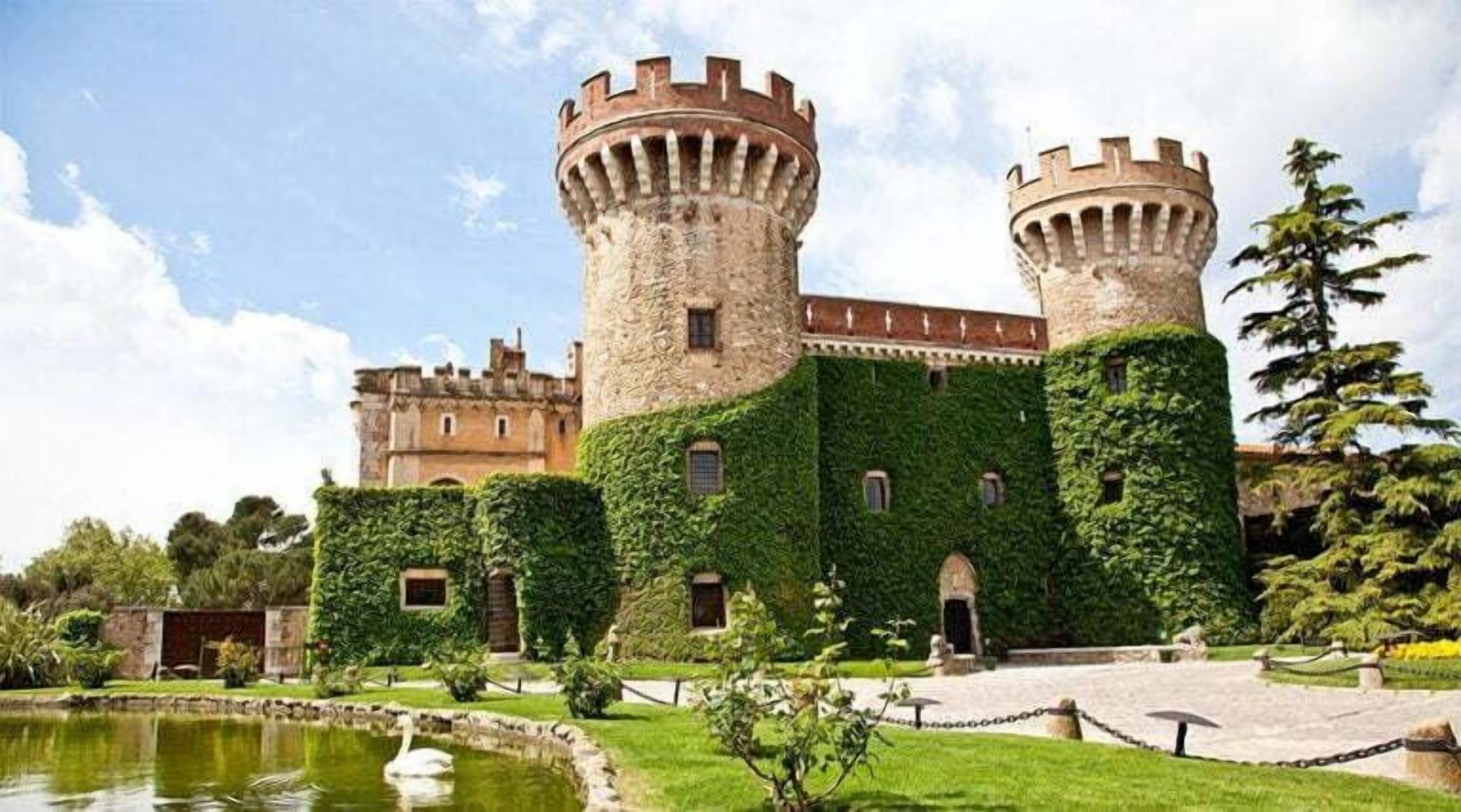 A castle with two towers, ivy-covered walls, a pond with a swan, and a well-maintained garden.