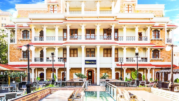 A large, multi-story hotel with a central courtyard, outdoor seating, and a pool. - FabHotel Rajwada Baner (Pune)