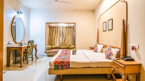 A hotel room with a bed, bedside table, nightstand, desk, chair, and a large mirror. - FabHotel Rajwada Baner (Pune)
