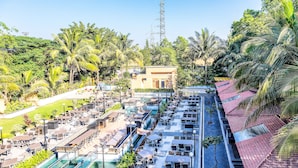 A resort with a swimming pool, outdoor seating, and palm trees. - FabHotel Rajwada Baner (Pune)