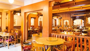 A restaurant with wooden furniture, round tables, and a warm interior. - FabHotel Rajwada Baner (Pune)