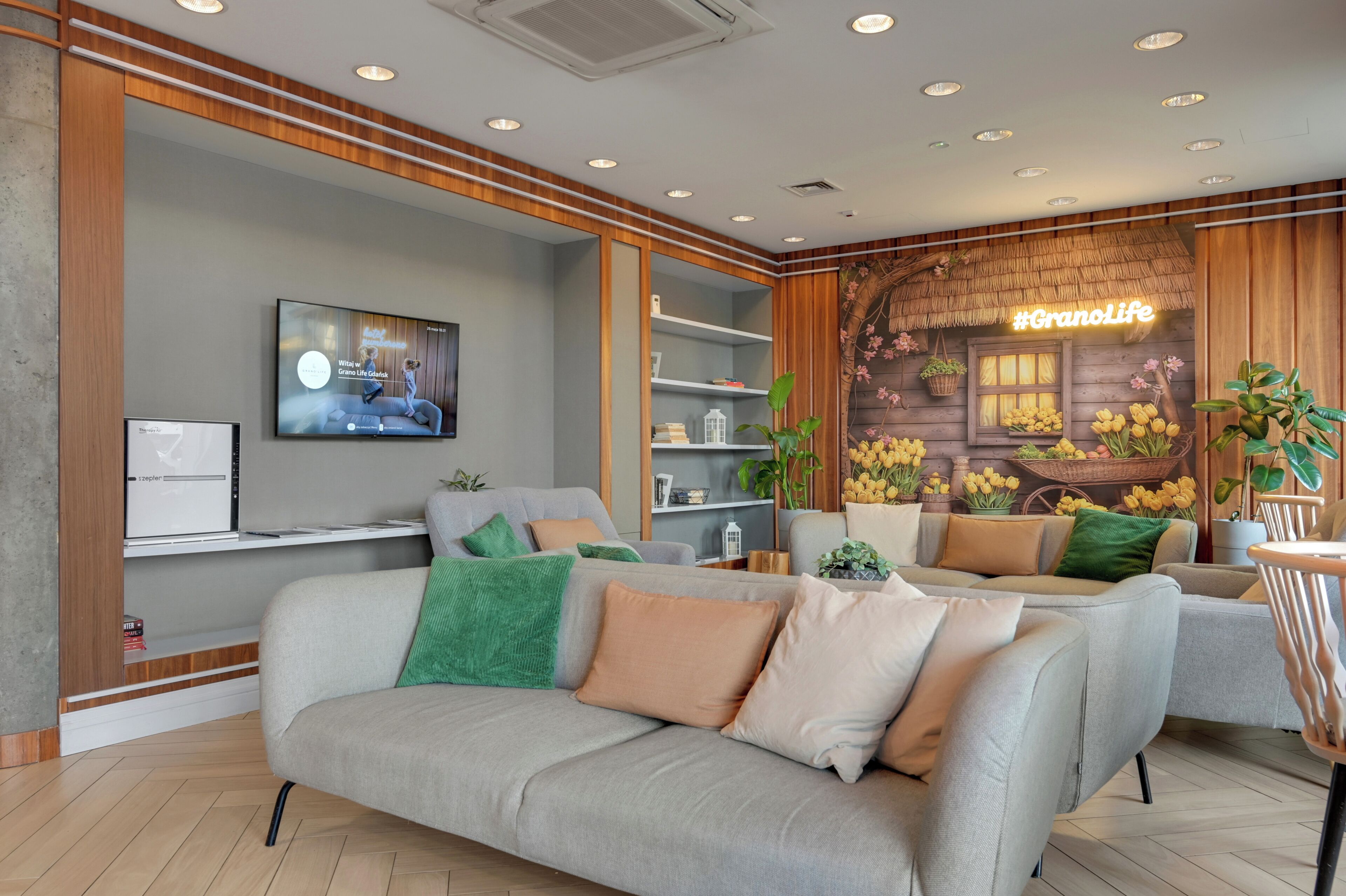 A modern living room with a grey sofa, a television, and a wooden wall with a neon sign.